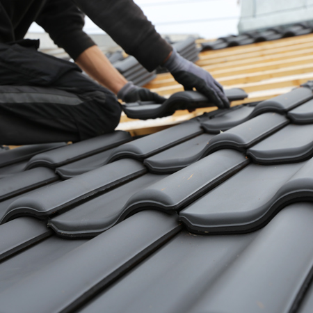 Person die ein Dach neu eindeckt